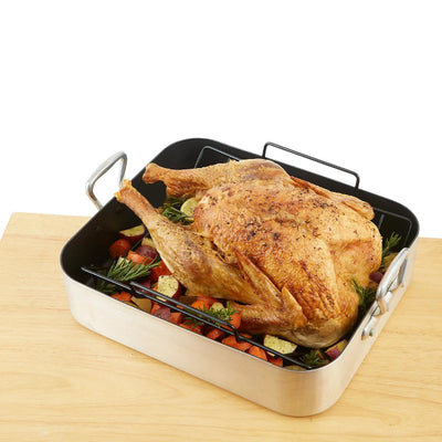 Roasted turkey with vegetables in a roasting pan on a wooden surface