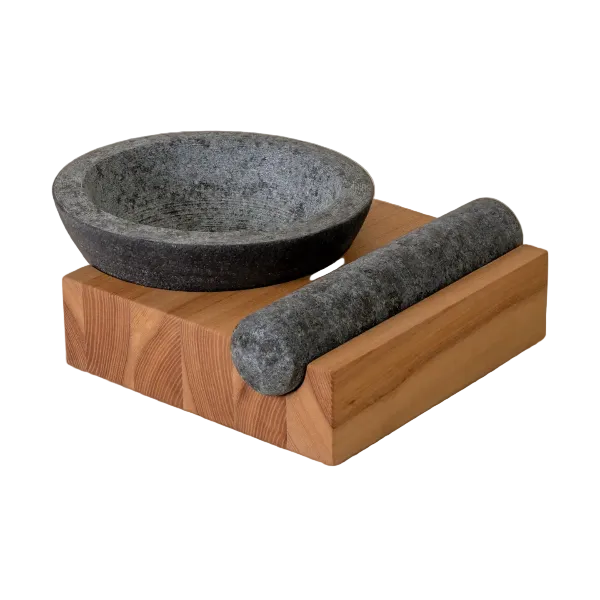 Stone mortar and pestle set on a wooden base against a beige background