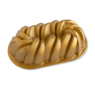 A gold-colored fluted loaf pan with a ribbed, pleated design, shown on a clean white background.
