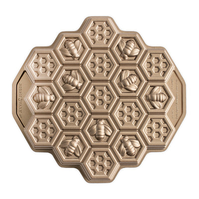 An octagonal metal baking mold featuring embossed honeycomb cells and bee motifs, shown from a top-down view on a plain white background.
