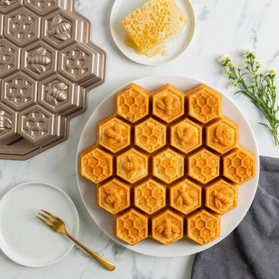 Hexagonal waffle maker with freshly made waffles on a plate, set on a marble surface.
