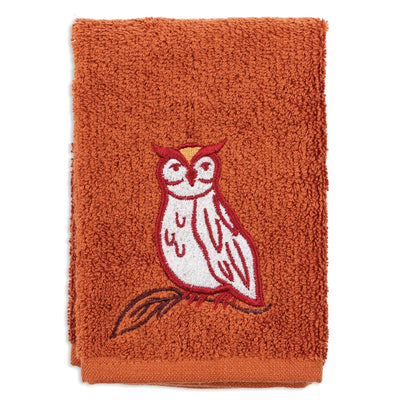 An orange terry cloth towel featuring an embroidered owl on a branch in red, white, and brown, set against a plain white background.